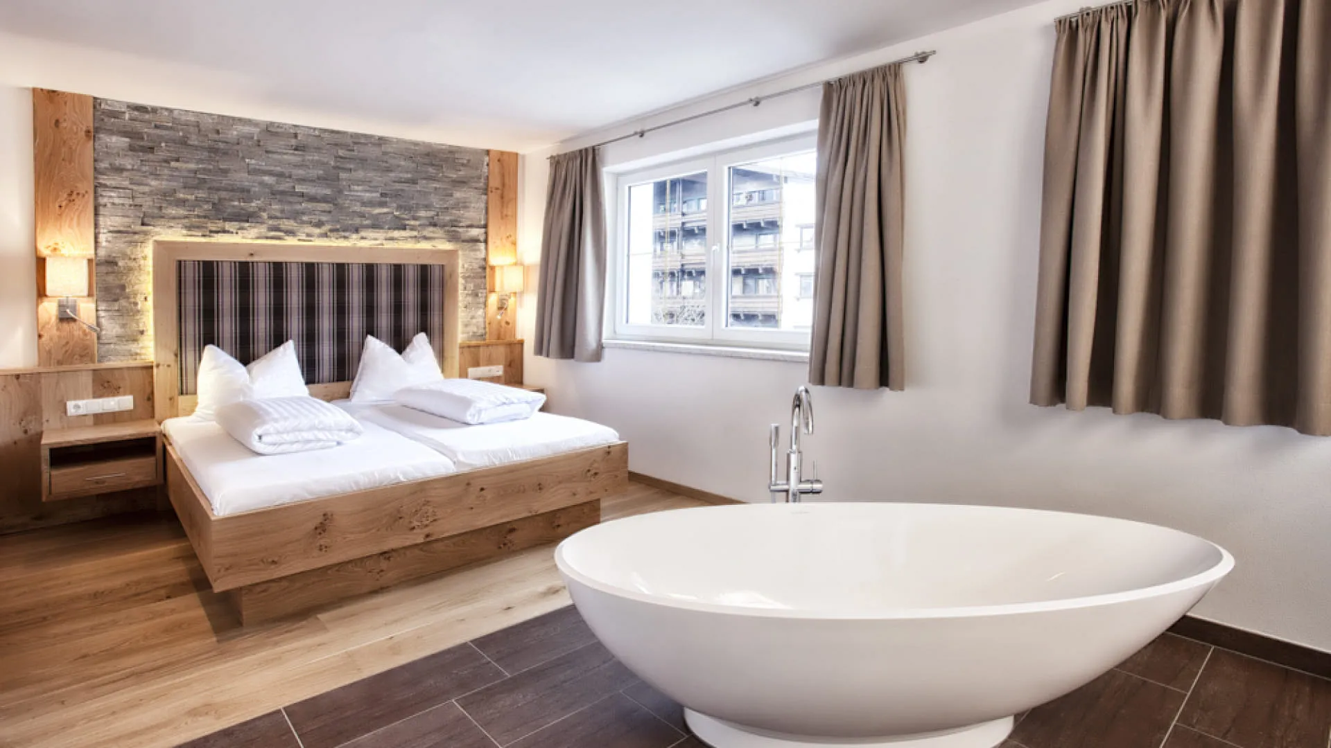 Helles modernes Schlafzimmer mit vielen Holzelementen und freistehender Badewanne