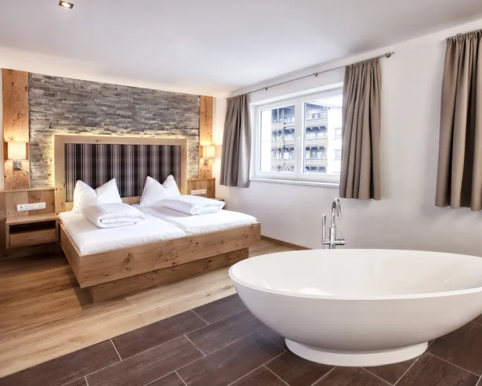 Modernes, helles Schlafzimmer mit freistehender Badewanne und Doppelbett