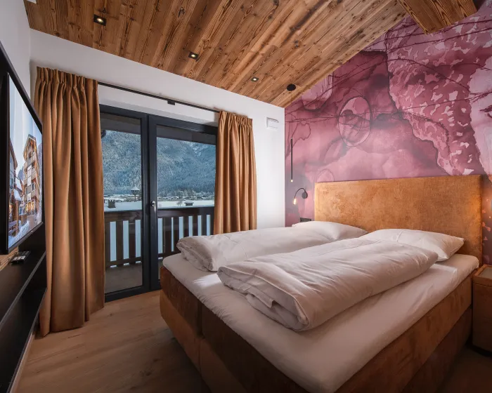 Doppelbett in Schlafzimmer mit Holzdecke und Designtapete 