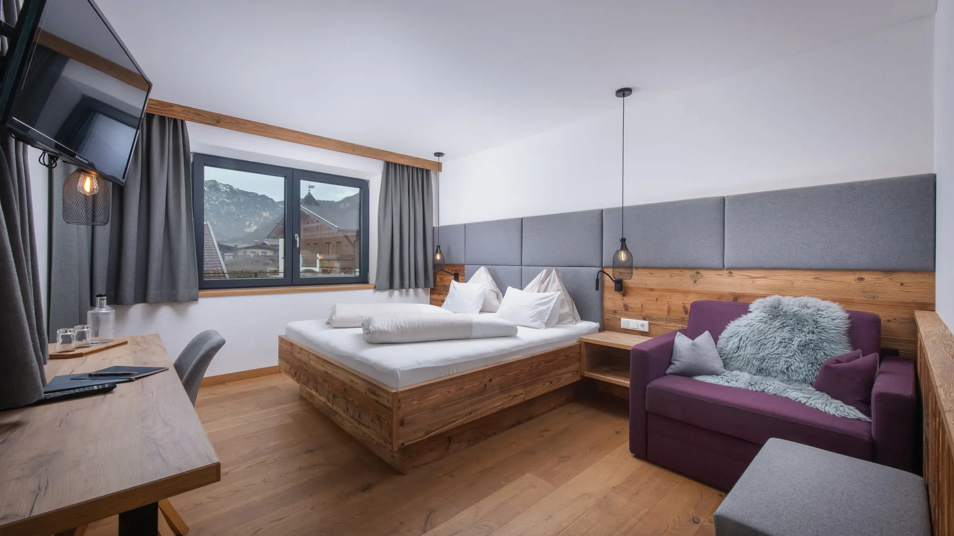 Helles, modernes Schlafzimmer mit Doppelbett, Tisch und großem Sessel