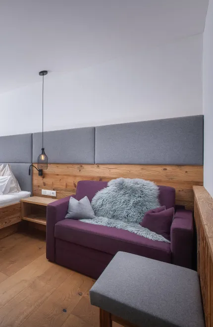 Helles, modernes Schlafzimmer mit Doppelbett und großem Sessel