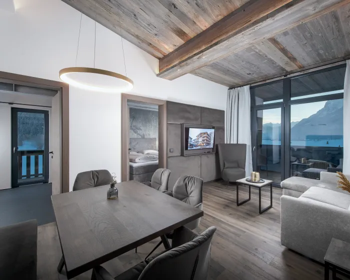 Helles, modernes Wohnzimmer mit Sitzbereich und angrenzender Couch in Grautönen
