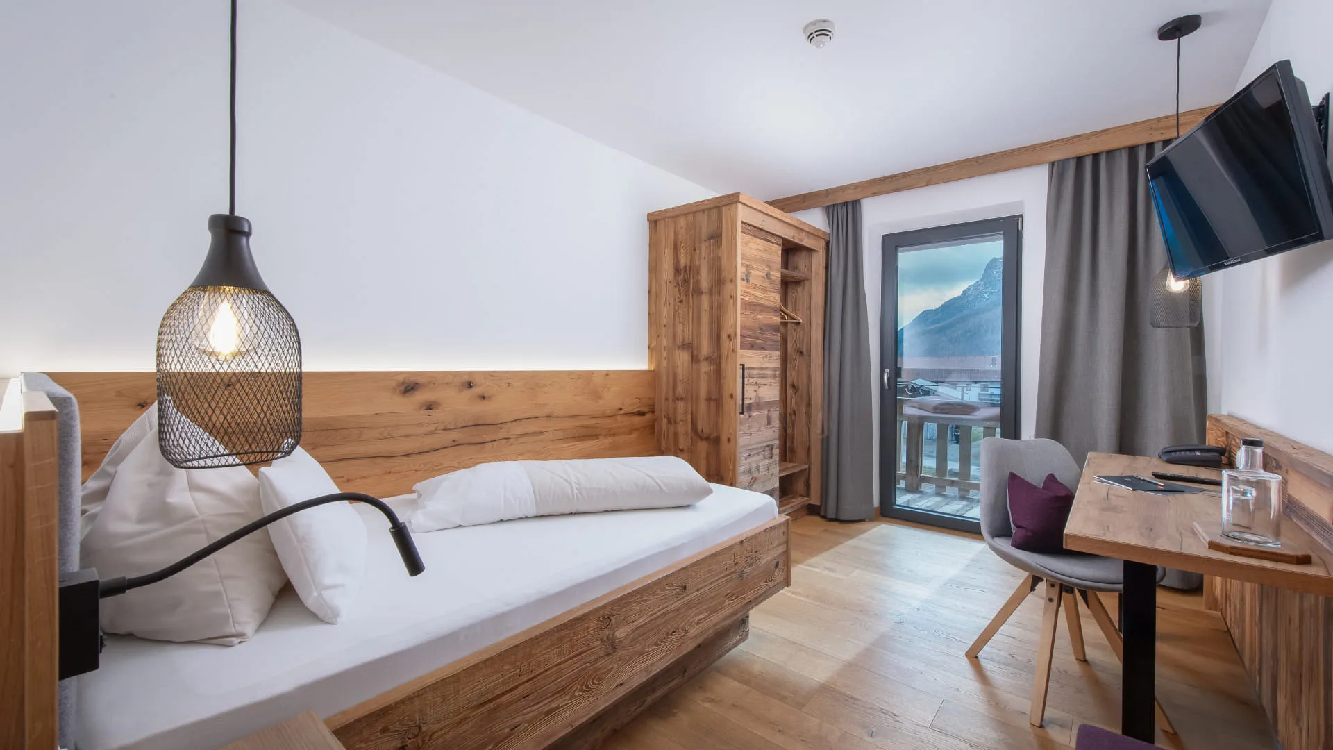 Helles, modernes Schlafzimmer mit Einzelbett, Tisch und Schrank