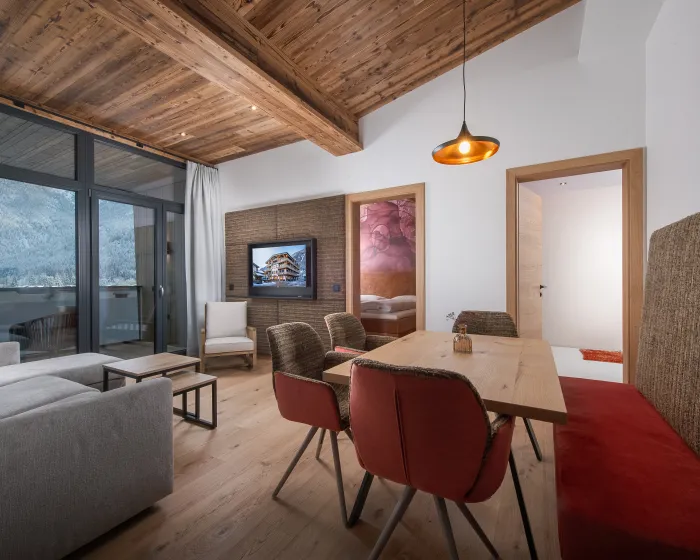 Helles, modernes Wohnzimmer mit Essbereich und Couch in Rottönen mit Holzelementen