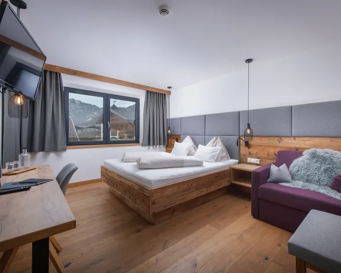 Helles, modernes Schlafzimmer mit Doppelbett, Tisch und Sessel