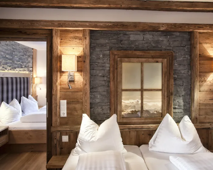 Nahaufnahme Doppelbett vor Holzwand mit angrenzendem weiteren Schlafzimmer