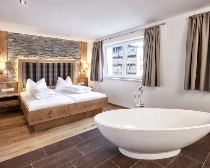 Helles, modernes Schlafzimmer mit großem Doppelbett und freistehender Badewanne